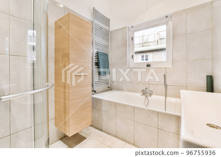 Sinks with mirrors and clean bathtub located near shower box with glass door in modern bathroom with white tiled walls 96755936
