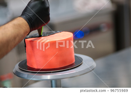 pastry chef decorating airbrush painted cup frosted icing cake with black filling on piping bag pastry chef decorating airbrush painted cup frosted icing cake with black filling on piping bag 96755989