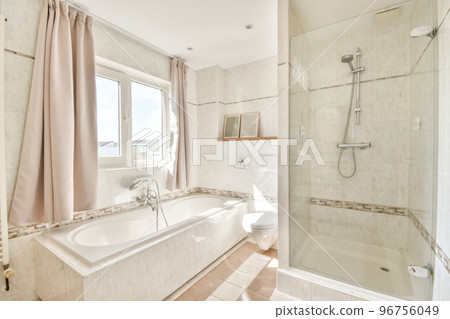 Stylish interior design of bathroom with mirror near sink and glass partition between shower tap and flush toilet 96756049