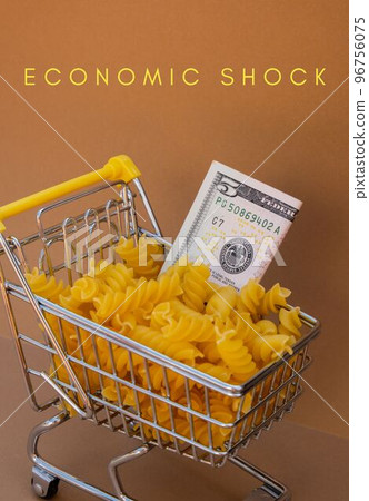 ECONOMIC SHOCK text against Shopping trolley cart Filled With Pasta with 5 US dollar paper money banknote on Beige background. Food and groceries shopping price increase, Rising food cost food crisis ECONOMIC SHOCK text against Shopping trolley cart Filled With Pasta with 5 US dollar paper money banknote on Beige background. Food and groceries shopping price increase, Rising food cost food crisis 96756075