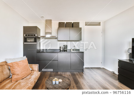 Contemporary open plan kitchen with dining table set and gray sofa in light spacious room 96756116