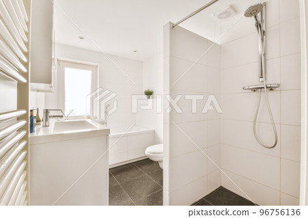 Modern flush toilet and ceramic sink installed on white tiled walls near mirror and towel in small restroom at home 96756136