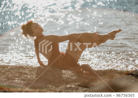 Woman in red dress on sea. Side view a Young beautiful sensual woman in a red long dress posing on the beach near sea on sunset. Girl on the nature on blue sky background. Fashion photo. 96756305