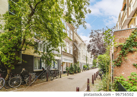 Panorama view of brick houses from an empty sidewalk street with trees and lanterns Panorama view of brick houses from an empty sidewalk street with trees and lanterns 96756502
