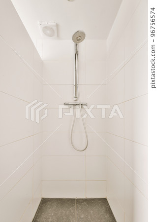 Modern flush toilet and ceramic sink installed on white tiled walls near mirror and towel in small restroom at home 96756574