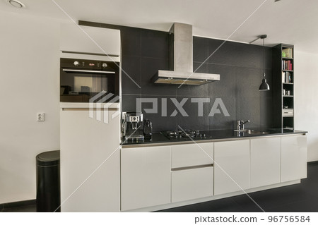 Table with chairs and flowers located near lounge area and kitchen in spacious room of contemporary apartment 96756584