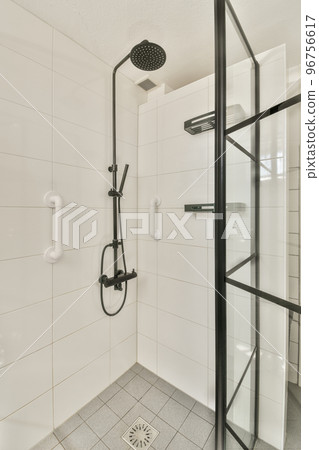 Flush toilet located between sink and shower in small tiled bathroom of contemporary apartment 96756617
