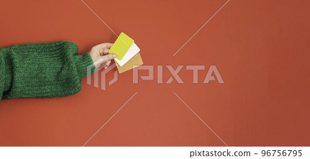Christmas shopping concept. Flat lie hands in a green sweater with bonus, gift or credit card. Banner on a red background Christmas shopping concept. Flat lie hands in a green sweater with bonus, gift or credit card. Banner on a red background 96756795