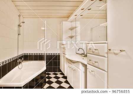 Sinks with mirrors and clean bathtub located near shower box with glass door in modern bathroom with white tiled walls 96756855