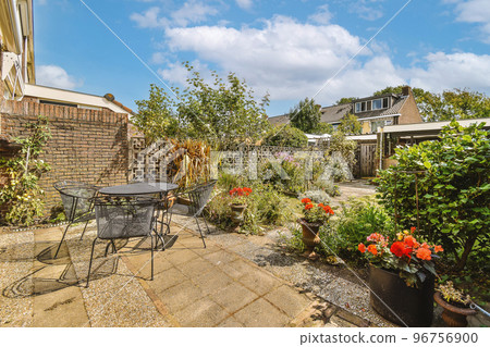Neat paved patio with sitting area and small garden near wooden fence 96756900