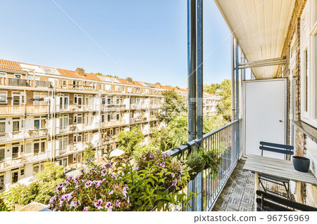 Narrow brick balcony with metal railings, wooden chair and door 96756969