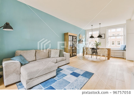 Stylish home interior design of spacious living room with large windows and white walls furnished with comfy couch and table on carpet on parquet floor Stylish home interior design of spacious living room with large windows and white walls furnished with comfy couch and table on carpet on parquet floor 96757058