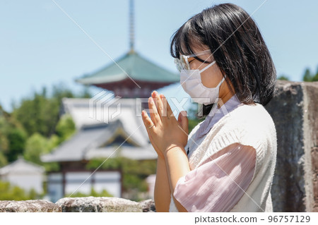 A young woman wearing a mask and praying A young woman wearing a mask and praying 96757129