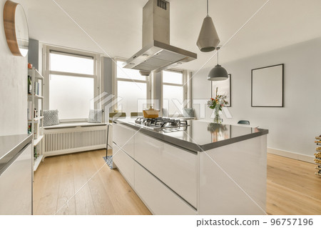 Table with chairs and flowers located near lounge area and kitchen in spacious room of contemporary apartment 96757196