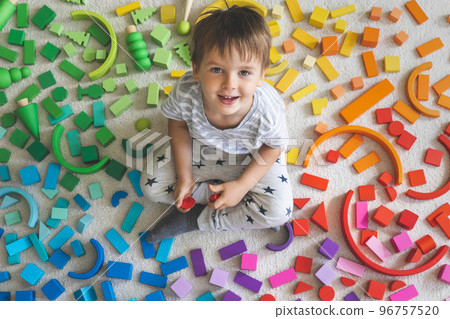 Wooden bricks Montessori material rainbow spectrum. Little cute boy plays with cubes. 96757520