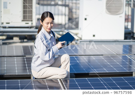 Young female worker inspecting solar panels Young female worker inspecting solar panels 96757598