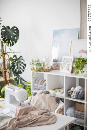 Modern workplace of tailor textile craft designer table with sewing machine and laptop near window 96757761