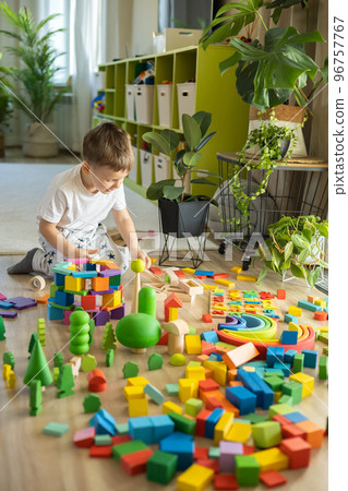 Confident male kid building fortress tower architecture and forest with trees wooden bricks ecology Montessori material 96757767
