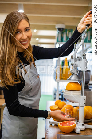 Portrait smiling woman bartender in apron cooking healthy detox refreshing juice orange grapefruits 96757930
