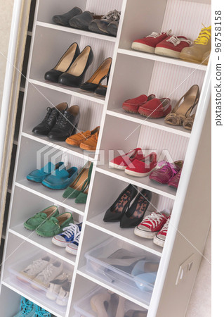 Empty domestic wardrobe interior with many female shoes neatly folded on shelves of cupboard 96758158