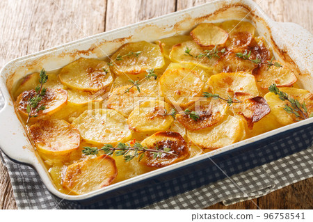 French Potato casserole with vegetable broth, herbs, onion and garlic close-up in a baking dish. horizontal 96758541