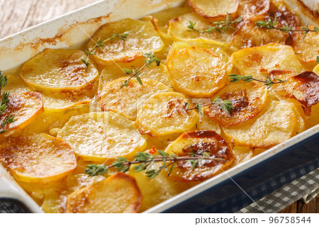 Potato gratin boulangere with onions, fresh thyme and butter closeup in the baking dish. Horizontal 96758544