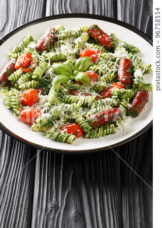 Fusilli pasta with italian sausages, tomatoes, pesto and parmesan close-up in a plate. Vertical Fusilli pasta with italian sausages, tomatoes, pesto and parmesan close-up in a plate. Vertical 96758554