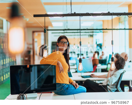 Female boss, manager executive posing in a modern startup office while being surrounded by her coworkers, team. 96758967