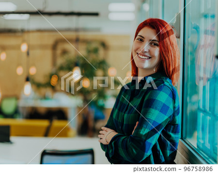 Headshot portrait of a modern woman with crossed arms in the office at night by the window 96758986