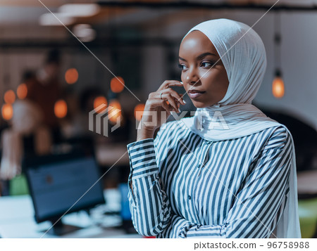 Protrait of a black ( african-american) female muslim standing in a modern business office while wearing a hijab. Protrait of a black ( african-american) female muslim standing in a modern business office while wearing a hijab. 96758988