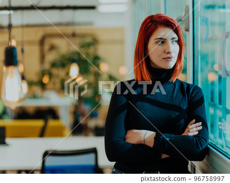 Headshot portrait of a modern woman with crossed arms in the office at night by the window 96758997