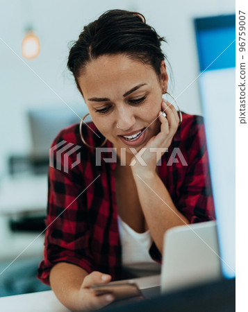 Woman sitting at workplace desk holds smartphone staring at laptop, synchronize data between computer and gadget in office, using corporate devices and business application, plan work, using organizer 96759007