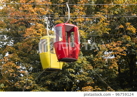 Red and yellow cable car cabins in autumn forest Red and yellow cable car cabins in autumn forest 96759124