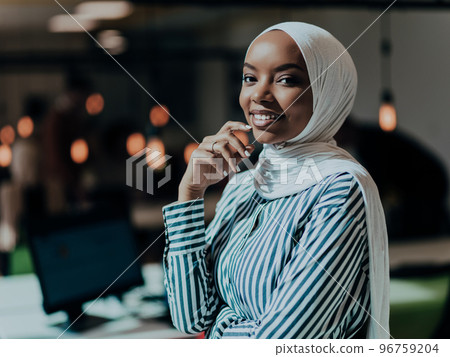 Protrait of a black ( african-american) female muslim standing in a modern business office while wearing a hijab. Protrait of a black ( african-american) female muslim standing in a modern business office while wearing a hijab. 96759204