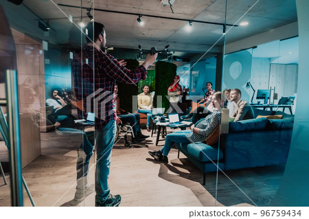 A bearded man in a modern office explaining to his young diverse team how a drone working  96759434