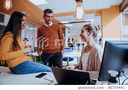 Group of multi-ethnic colleagues working on desktop computers, laptop and sharing their ideas in a modern office space.Young influencers work on online marketing projects. Group of multi-ethnic colleagues working on desktop computers, laptop and sharing their ideas in a modern office space.Young influencers work on online marketing projects. 96759441
