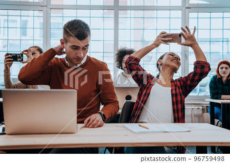 A group of diverse young men and women sit in a modern classroom and listen to a lecture on business training A group of diverse young men and women sit in a modern classroom and listen to a lecture on business training 96759498