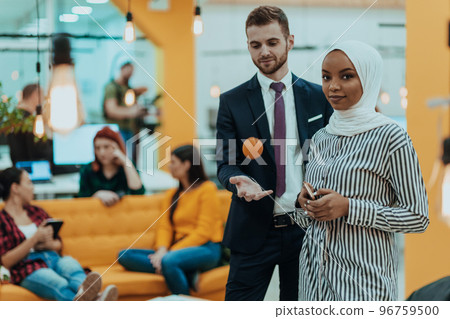 Portrait of a formal businessman and young African American businesswoman posing with their team in a modern startup office. Marketing concept. Multi-ethnic society. 96759500