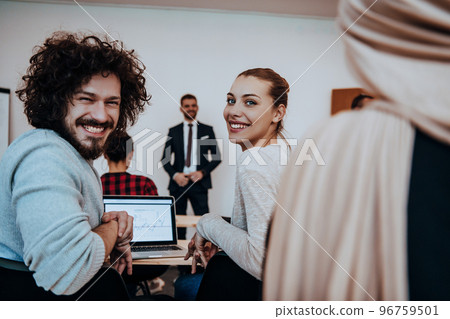 A group of diverse people listen to a lecture in business training while sitting in a modern classroom A group of diverse people listen to a lecture in business training while sitting in a modern classroom 96759501