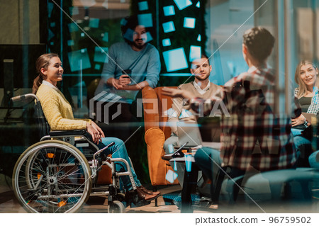 Businesswoman in wheelchair having business meeting with team at modern office. A group of young freelancers agree on new online business projects Businesswoman in wheelchair having business meeting with team at modern office. A group of young freelancers agree on new online business projects 96759502