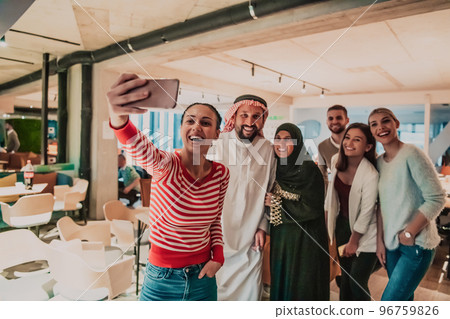 Diverse team of businessmen taking selfie photos on smartphone while in modern office 96759826