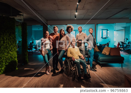 Businesswoman in a wheelchair on break in a modern office with her team in the background 96759863