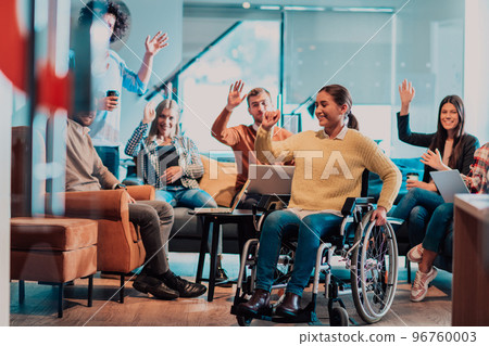 Businesswoman in wheelchair having business meeting with team at modern office. A group of young freelancers agree on new online business projects 96760003