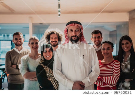 A diverse group of successful business people in a modern glass office stand together at the top with their Arab leader director A diverse group of successful business people in a modern glass office stand together at the top with their Arab leader director 96760021