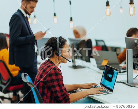 Group of multi-ethnic colleagues working on desktop computers, laptop and sharing their ideas in a modern office space.Young influencers work on online marketing projects. 96760030