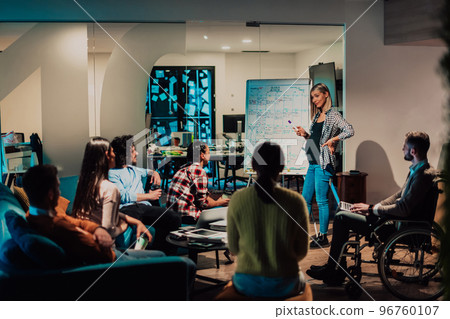 A pregnant businesswoman leads a creative meeting of a diverse business team in a modern coworking 96760107