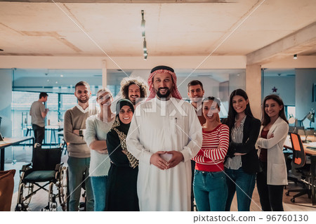 A diverse group of successful business people in a modern glass office stand together at the top with their Arab leader director A diverse group of successful business people in a modern glass office stand together at the top with their Arab leader director 96760130