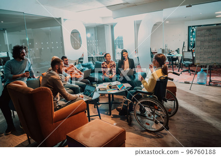 Businesswoman in wheelchair having business meeting with team at modern office. A group of young freelancers agree on new online business projects 96760188