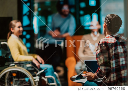 Businesswoman in wheelchair having business meeting with team at modern office. A group of young freelancers agree on new online business projects Businesswoman in wheelchair having business meeting with team at modern office. A group of young freelancers agree on new online business projects 96760368