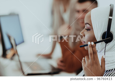 African American muslim woman with hijab and headset working as customer support in a modern office. 96760413